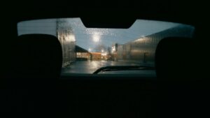 雨の夜に停車した車の後部座席から見た駐車場