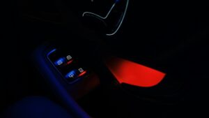 夜の車内。ドアパネルのスイッチが青く光り、足元に赤い間接照明が映っている