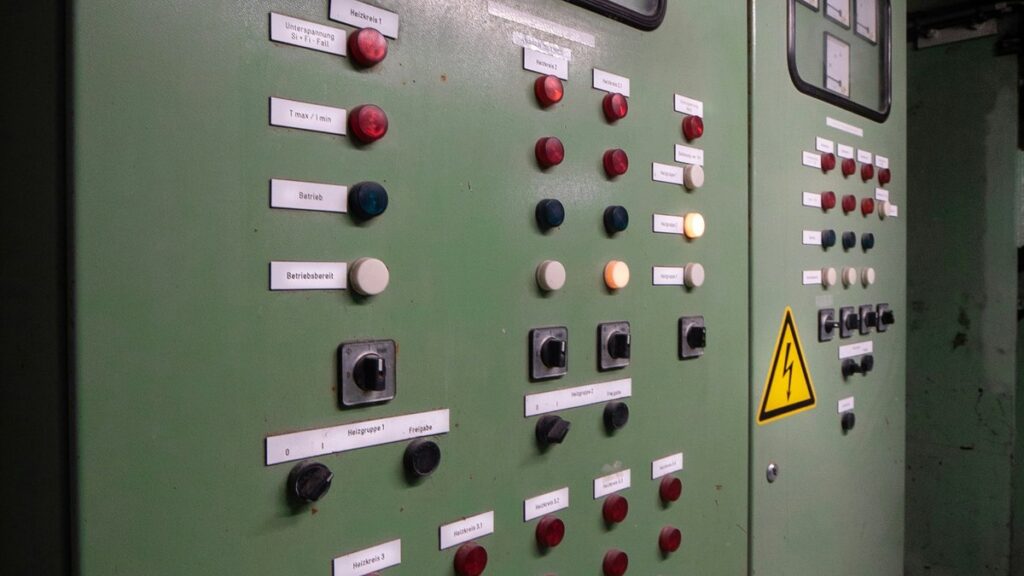 受変電設備の制御盤。表示灯と切替スイッチが並び、右側に高電圧注意の警告表示がある
