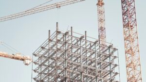 クレーンに囲まれて組み上がる建設中の鉄骨