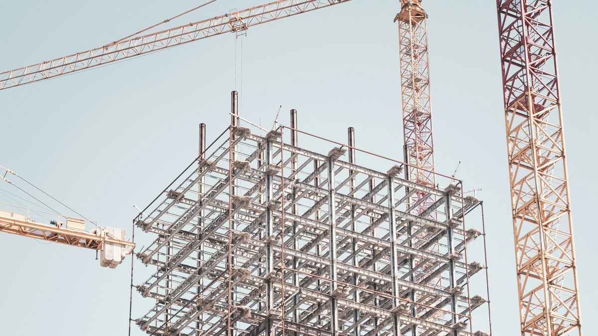 クレーンに囲まれて組み上がる建設中の鉄骨