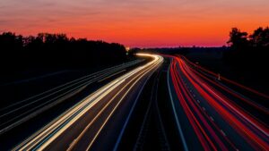夜明けの空の下で車のライトが流れる高速道路