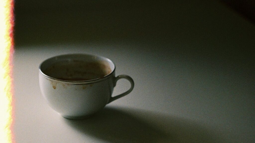 薄暗いテーブルに置かれたコーヒーカップ