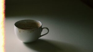 薄暗いテーブルに置かれたコーヒーカップ